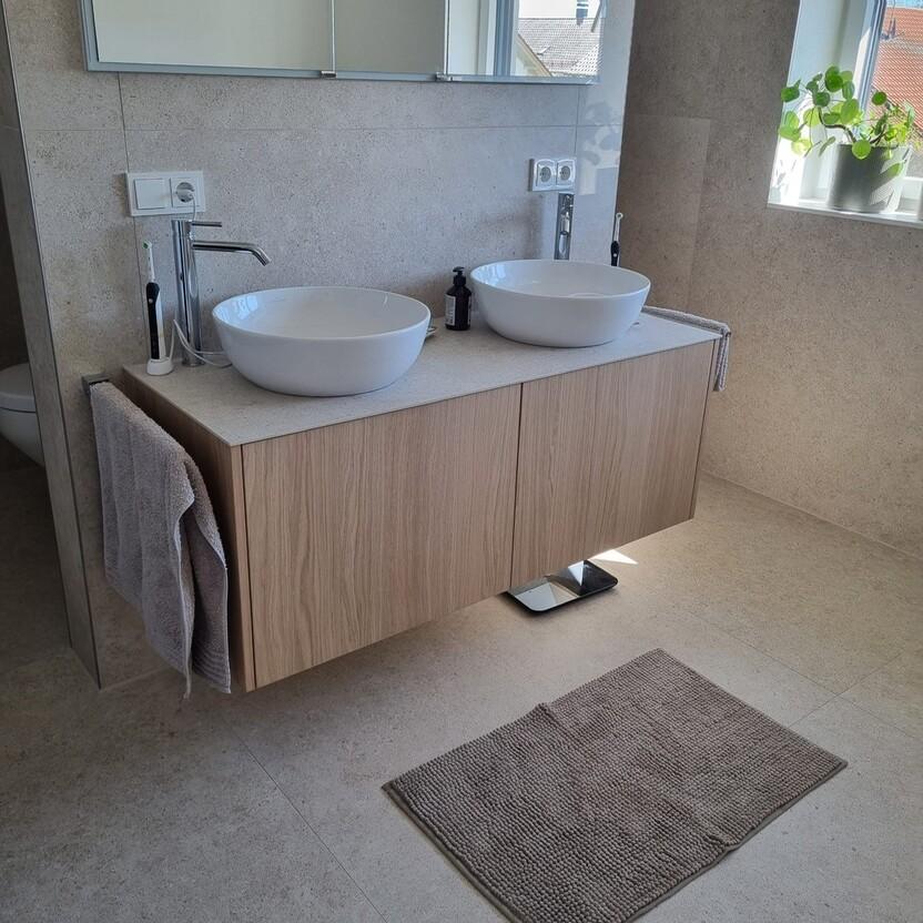 Moderner Doppelwaschtisch mit weißen Aufsatzbecken und Unterschrank aus heller Eiche.