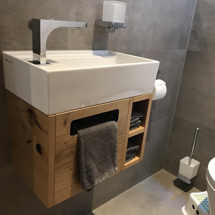 Hänge-Waschtisch aus Eiche mit offenen Regalen, Metallarmatur und Toilettenzubehör.