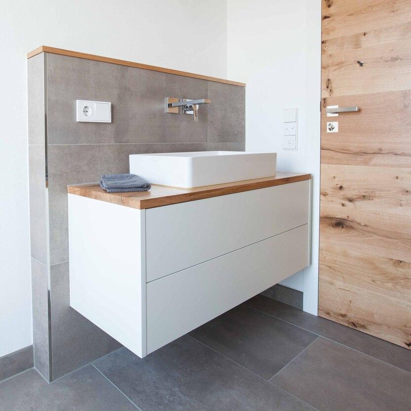 Badezimmer mit Holz und Weißtönen, unterbauertem Becken und grauen Fliesen
