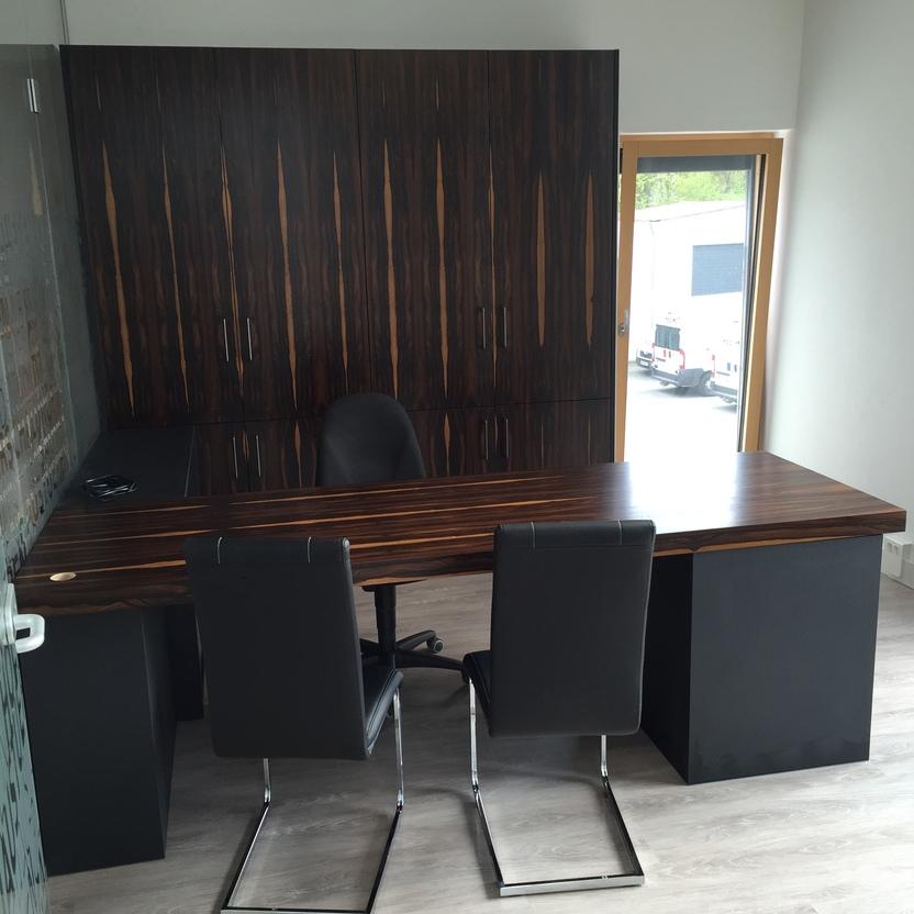 Büromöbel nach Maß mit dunklem Schreibtisch und passender Schrankwand in edler Holzoptik in einem modernen Büro