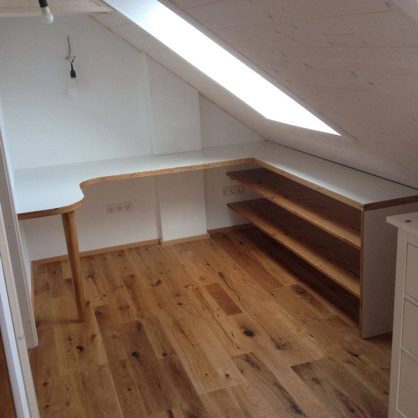 Büromöbel nach Maß unter Dachschräge mit weißer Arbeitsplatte, Holzdetails und offenen Regalfächern