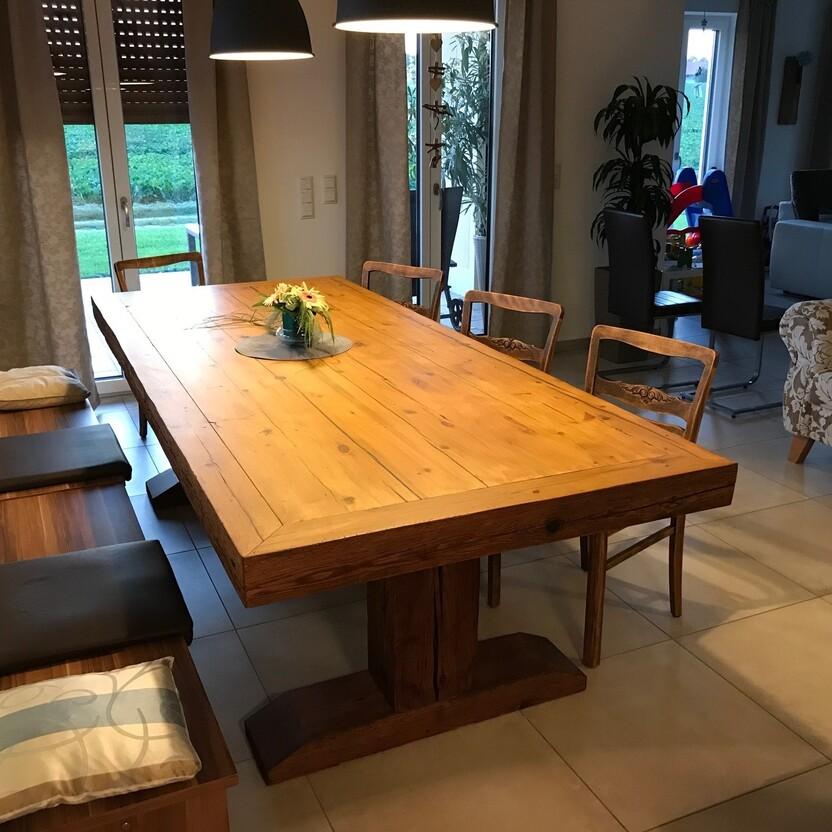 Holztisch mit Bänken in einem hellen Esszimmer, angrenzend zum Wohnbereich