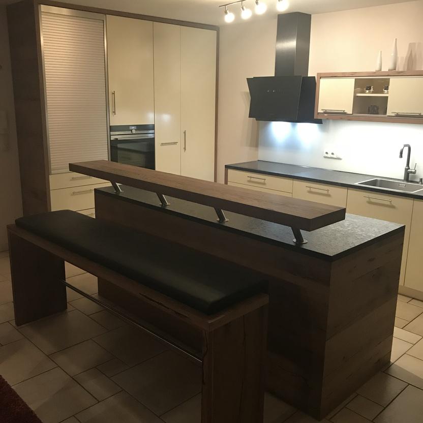 Moderne Küchenmöbel mit heller Front, dunkler Arbeitsplatte und Kochinsel aus Altholz mit integrierter Sitzbank