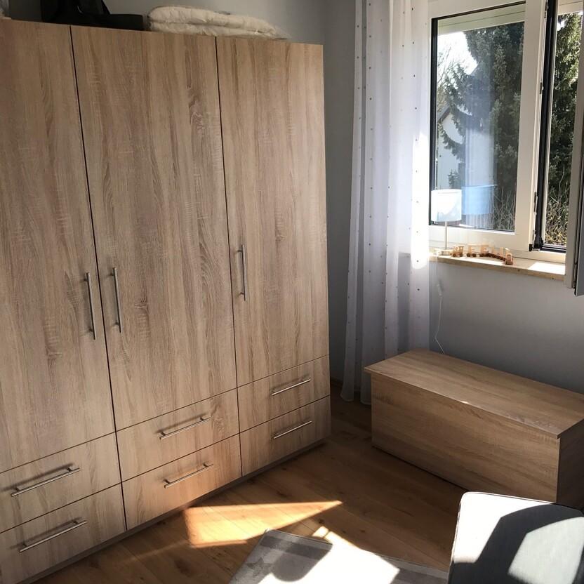 Heller Kleiderschrank und Holztruhe aus Eiche mit viel Stauraum im Schlafzimmer.