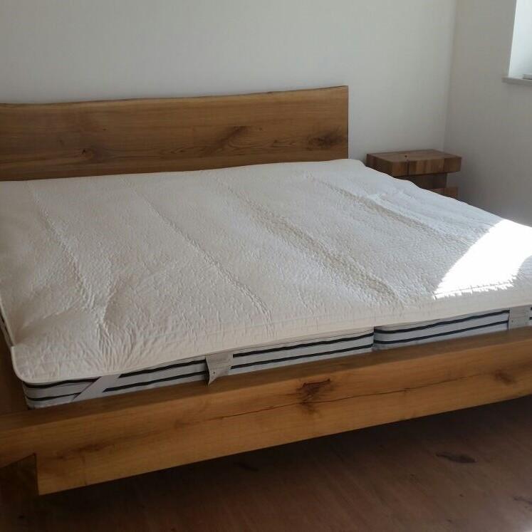 Massivholzbett aus geölter Eiche mit schlichtem Design und zwei passenden Nachttischen.