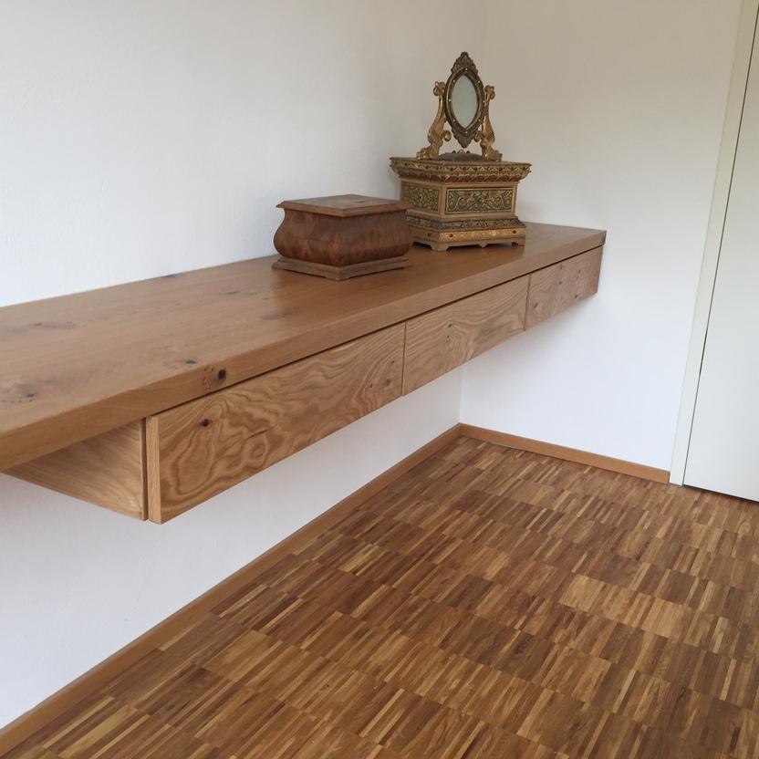 Wandmontierte Holzkonsole mit Schubladen, darauf eine Schmuckschatulle und ein Spiegel.