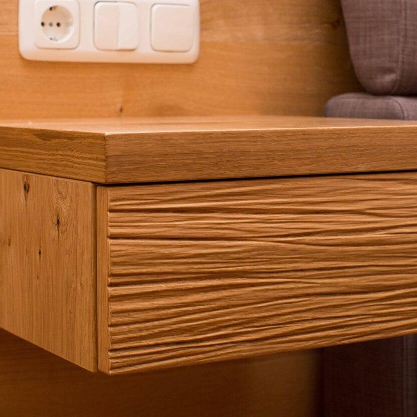 Moderner Nachttisch aus geölter Eiche mit strukturierter Front und integriertem Steckdosenelement.