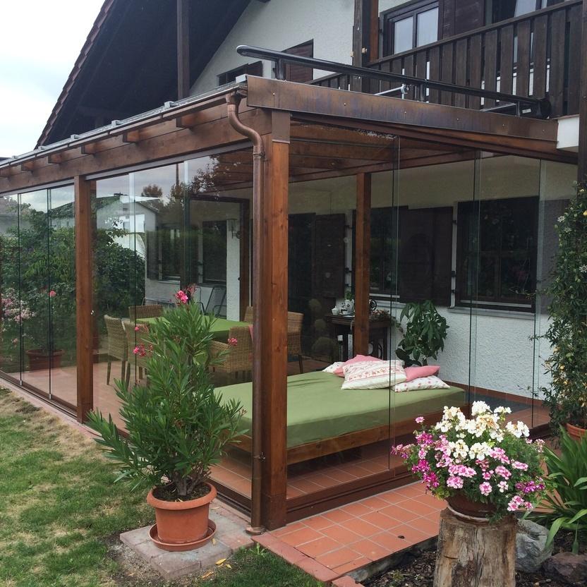 Wintergarten mit Holzrahmen und Glasfront an einem Haus im Landhausstil, umgeben von Blumen und Terrasse