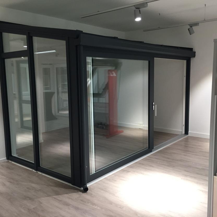 Wintergarten mit anthrazitfarbenem Aluminiumrahmen und Schiebet&uuml;ren als Ausstellungsmodell im Innenraum