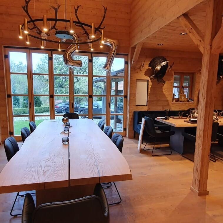 Rustikales, holzverkleidetes Esszimmer mit großem Tisch und modernen Stühlen, optimiert durch Innenausbau nach Maß.