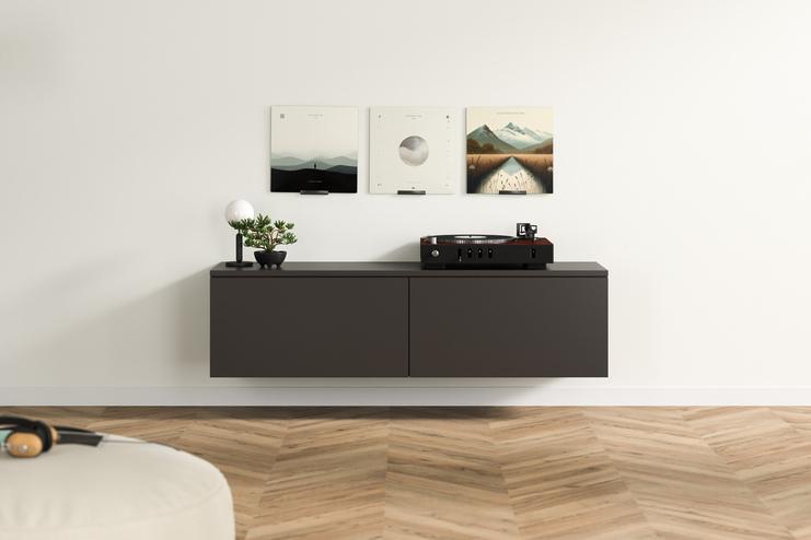 Dunkelgraues, maßgefertigtes Hängeboard mit klaren Linien und Plattenspieler, akzentuiert durch eine Pflanze und kunstvolle Bilder an der Wand darüber.
